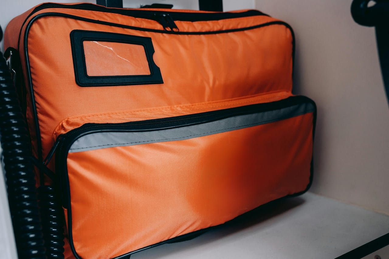 Close-up of an orange emergency medical bag with visible zippers and compartments.
