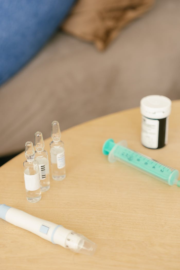 Close-up of medical supplies including ampoules and syringe on a table.